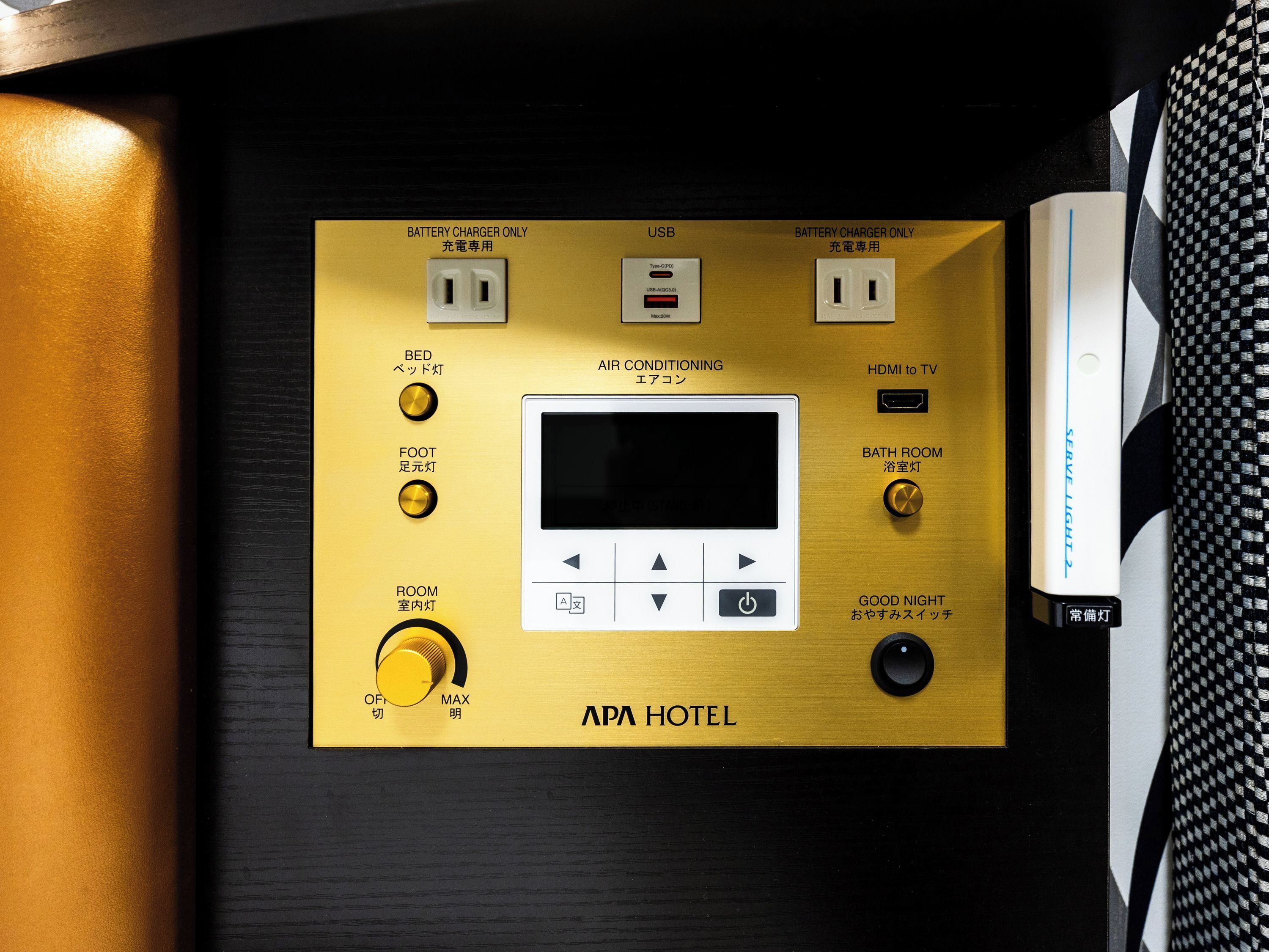 A control panel with a screen, USB port, and various switches for room and bathroom lighting, labeled "APA HOTEL".