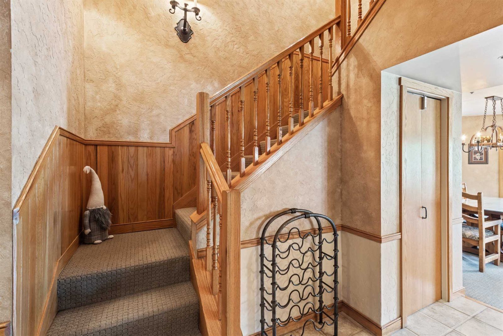 A wooden staircase with a metal railing, carpeted steps, and a wall-mounted light fixture.