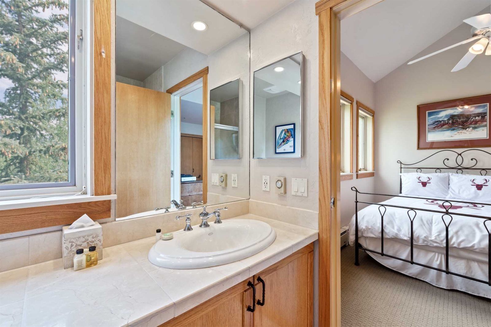 A modern bathroom with a large mirror, a white sink, and a bed with a metal frame.