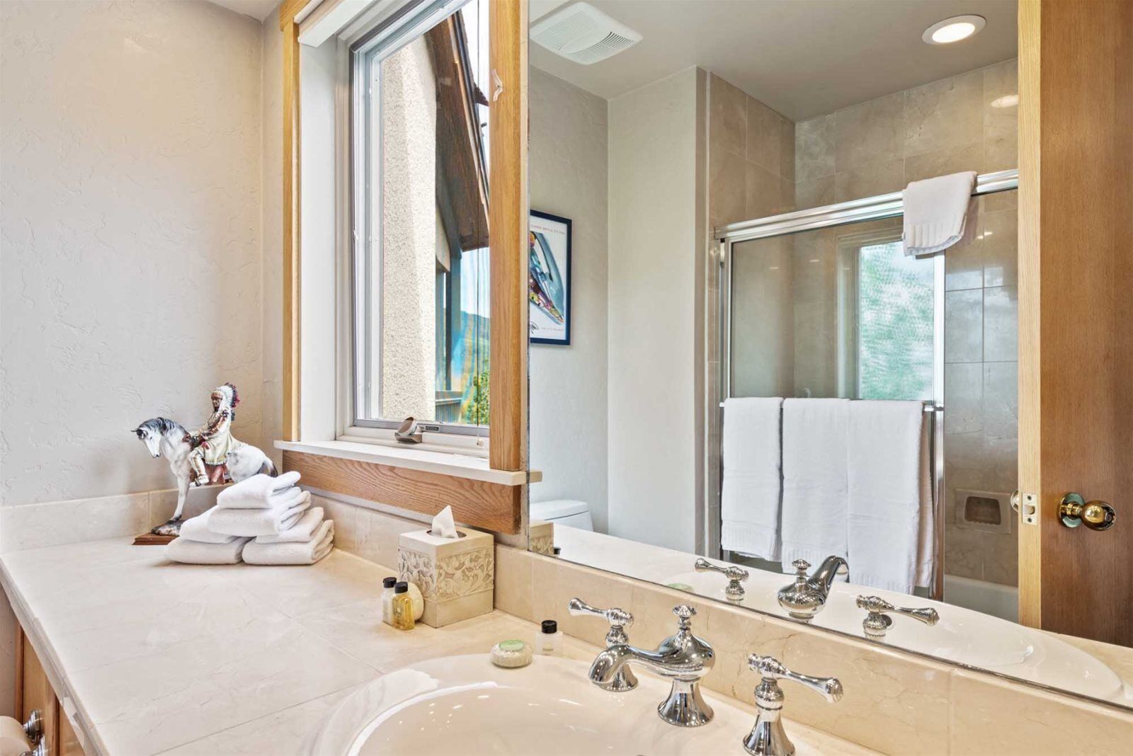 A modern bathroom with a large mirror, a sink, and a shower.