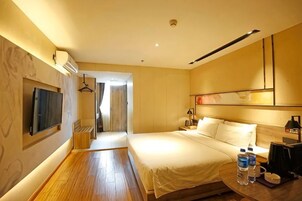 Una habitación de hotel con cama, mesita de noche, televisor y suelo de madera.