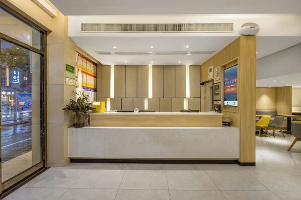 A hotel reception area with a counter, seating, and a view of the street outside.
