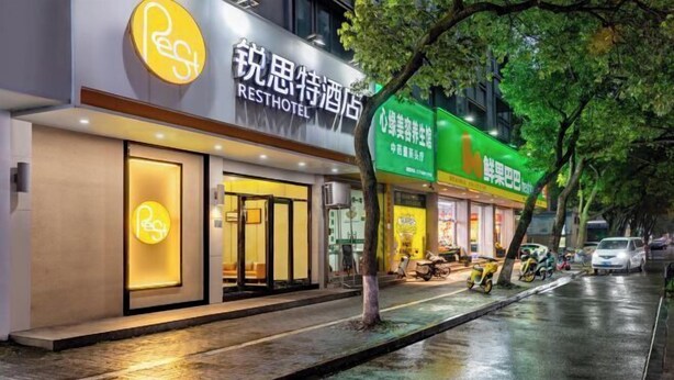 A hotel with a modern facade, a prominent sign, and a well-lit entrance. - Rest Motel Hotel Taizhou Luqiao 2nd (Taizhou)
