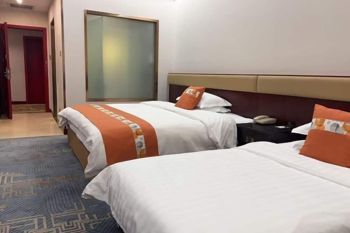Habitació d'hotel amb dos llits, una tauleta de nit, un telèfon i una porta que dona a una altra habitació.