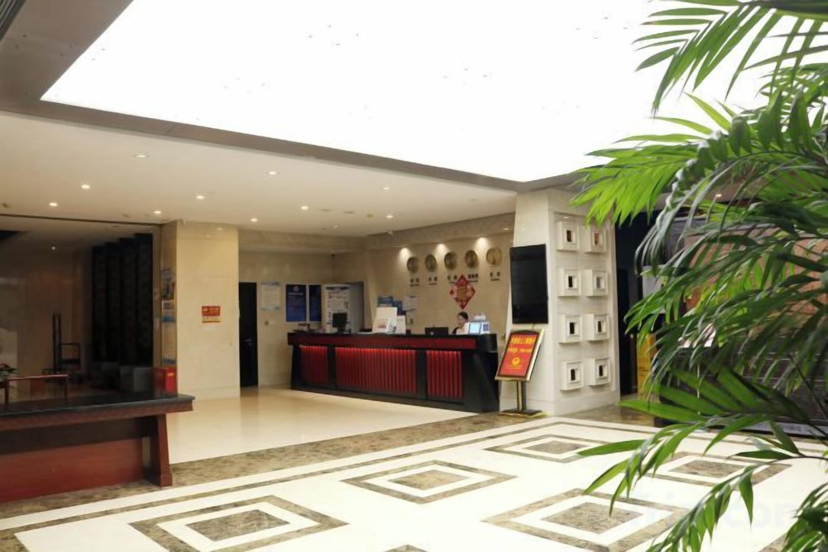 Un hall d’hôtel avec un comptoir d’accueil, une plante et un sol à motifs.