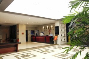 Eine Hotelhalle mit einer Rezeption, einer Pflanze und einem gemusterten Boden.