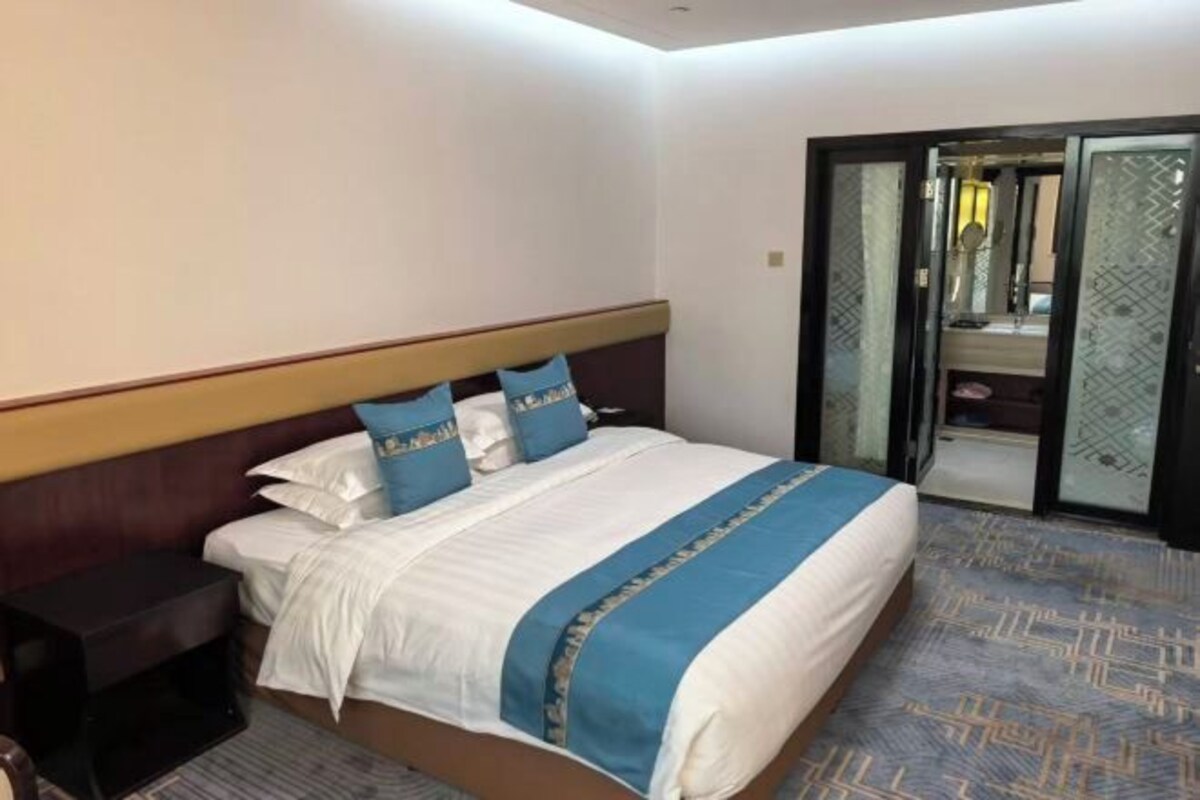 A hotel room with a bed, a nightstand, a mirror, and a sliding door.