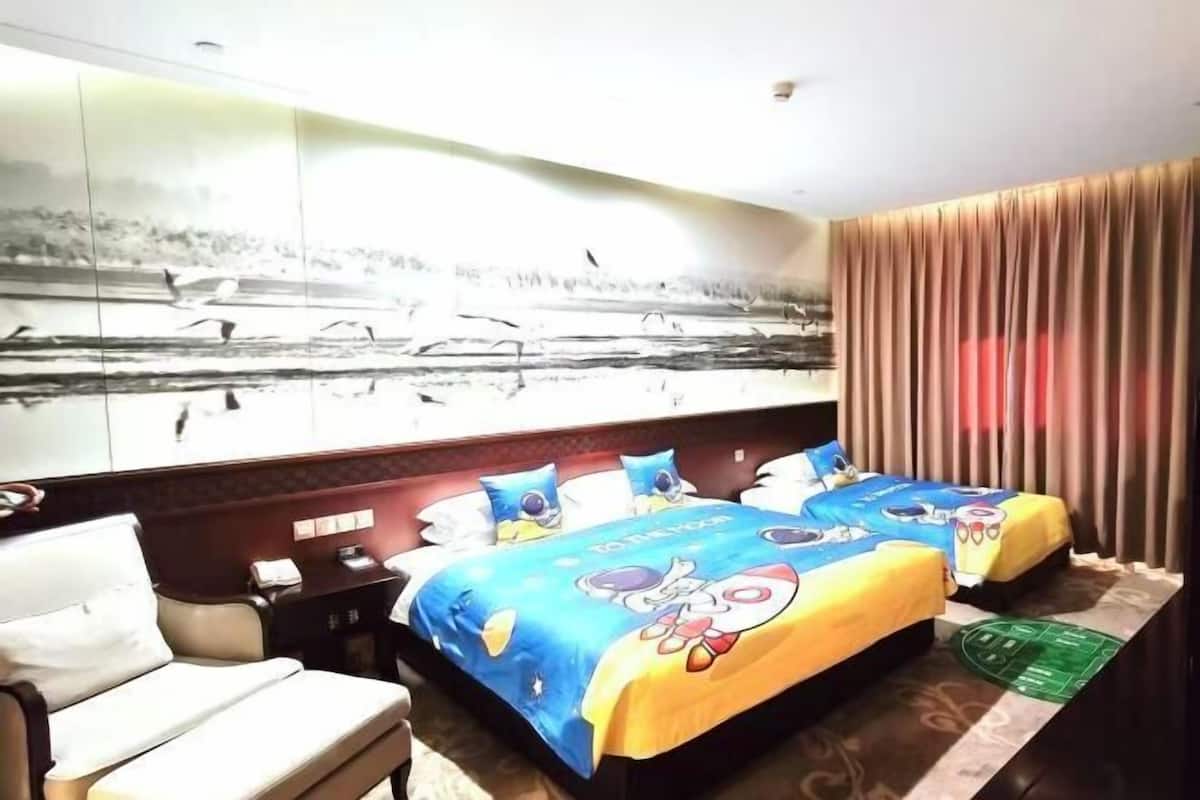 Habitació d'hotel amb un llit gran, una taula de treball, una cadira i un mirall gran.