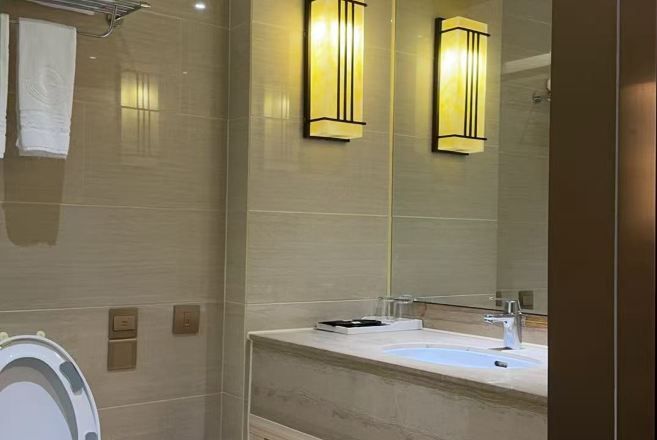 A bathroom with a large mirror, a sink, and two wall-mounted light fixtures.