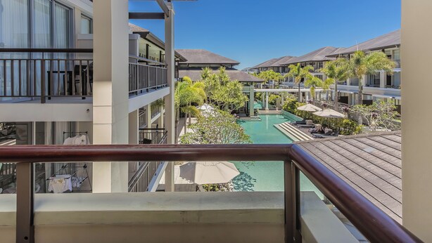 Un hôtel à plusieurs étages doté de balcons, d’une piscine et d’un aménagement paysager luxuriant.
