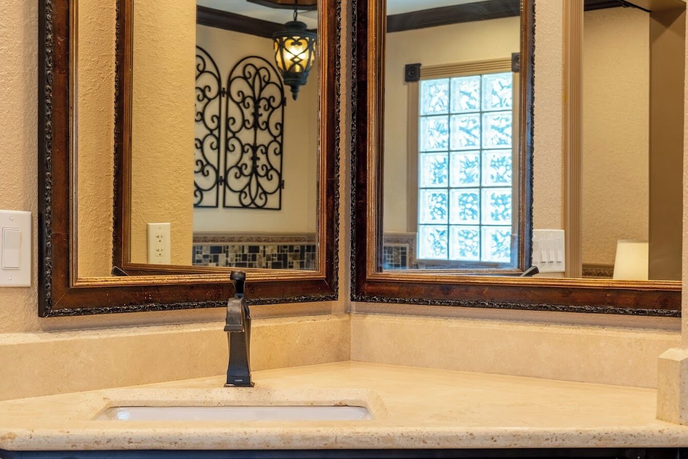 Un baño con un lavamanos, dos espejos y un adorno en la pared.