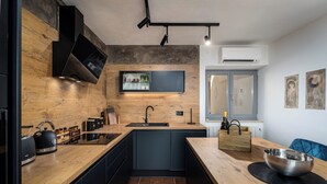 A modern kitchen with a wooden countertop, black cabinets, a built-in stove, and a window with a view.
