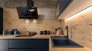 A modern kitchen with a wooden countertop, black cabinets, a built-in stove, and a black sink.