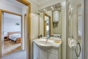 A modern bathroom with a large sink, mirror, and shower.
