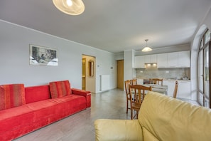 A modern apartment with a red sofa, yellow armchair, and a dining area with wooden chairs and a table.