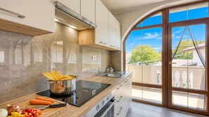 A modern kitchen with a stove, sink, and large windows.