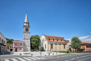A historic church with a bell tower, a red-roofed building, and a pedestrian crossing.