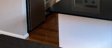 A modern kitchen with a stainless steel refrigerator, a dishwasher, a sink, and a built-in washing machine.