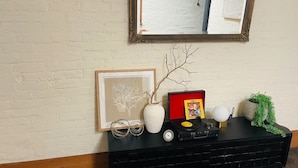 A black console table with a framed picture, a white vase with a branch, a record player, and a small potted plant. - Cozy Bluestone House in Norwood – Perfect for Families and Their Pets (Norwood)