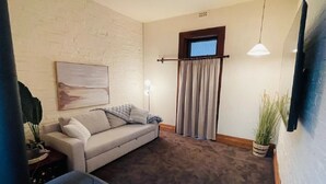 A living room with a sofa, a small table, and a potted plant. - Cozy Bluestone House in Norwood – Perfect for Families and Their Pets (Norwood)