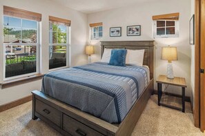 A bedroom with a large bed, two bedside tables with lamps, a window with a view of the outdoors, and a small table with a lamp. - Darling Dover Sleeps 8 - Marina, beach, trails (Dover)