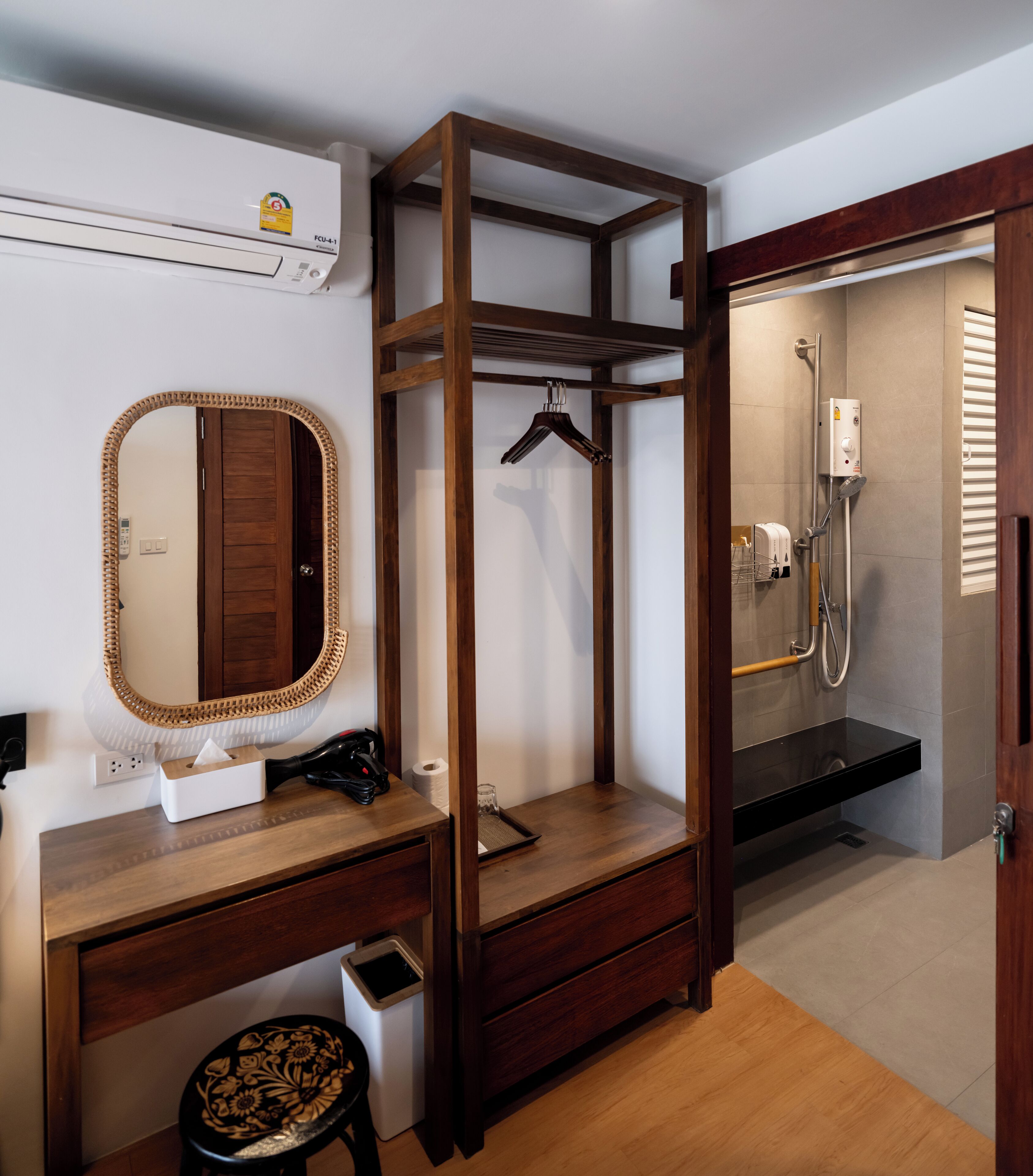A bathroom with a wooden vanity, a mirror, a towel rack, a shower area, and a toilet.