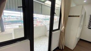 A room with a large window, a door, and a view of buildings outside.