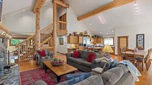 A spacious living area with a wooden staircase, a dining table, and a kitchen in the background. - Mountain chalet w/ hot tub & games (Whistler)