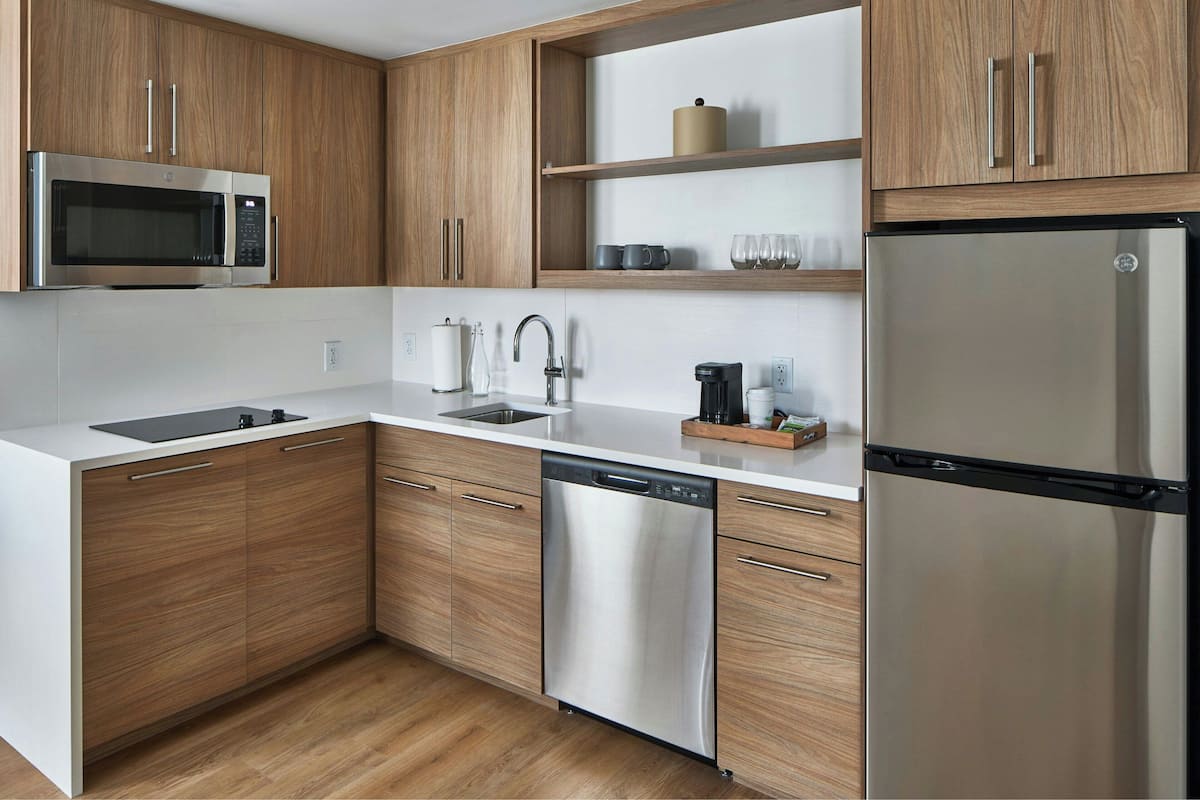 A modern kitchen with wooden cabinets, stainless steel appliances, and a white countertop.