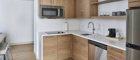 Een moderne keuken met houten kastjes, roestvrijstalen apparatuur en een wit aanrecht.