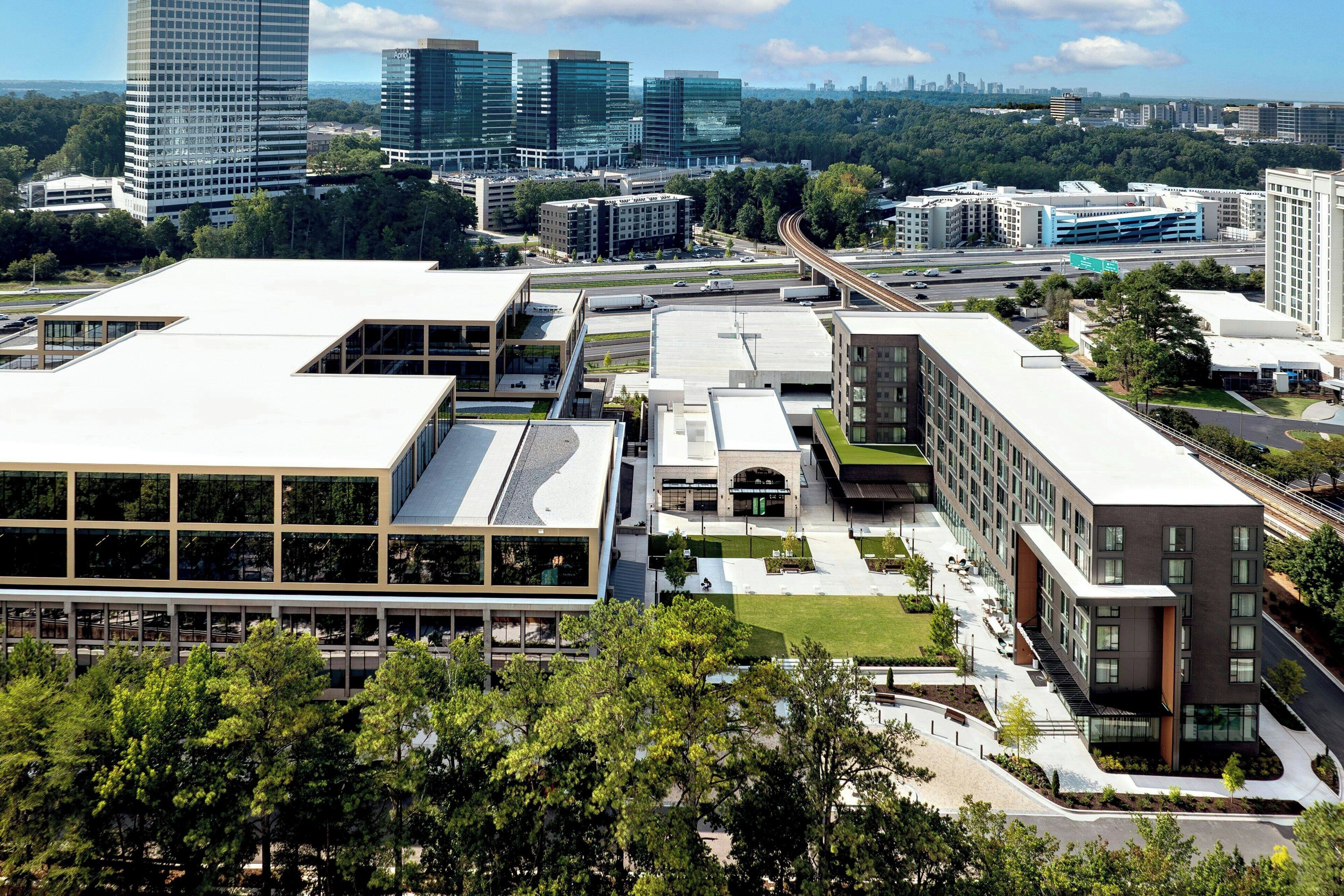 A modern building complex with multiple floors, large windows, and a green roof.