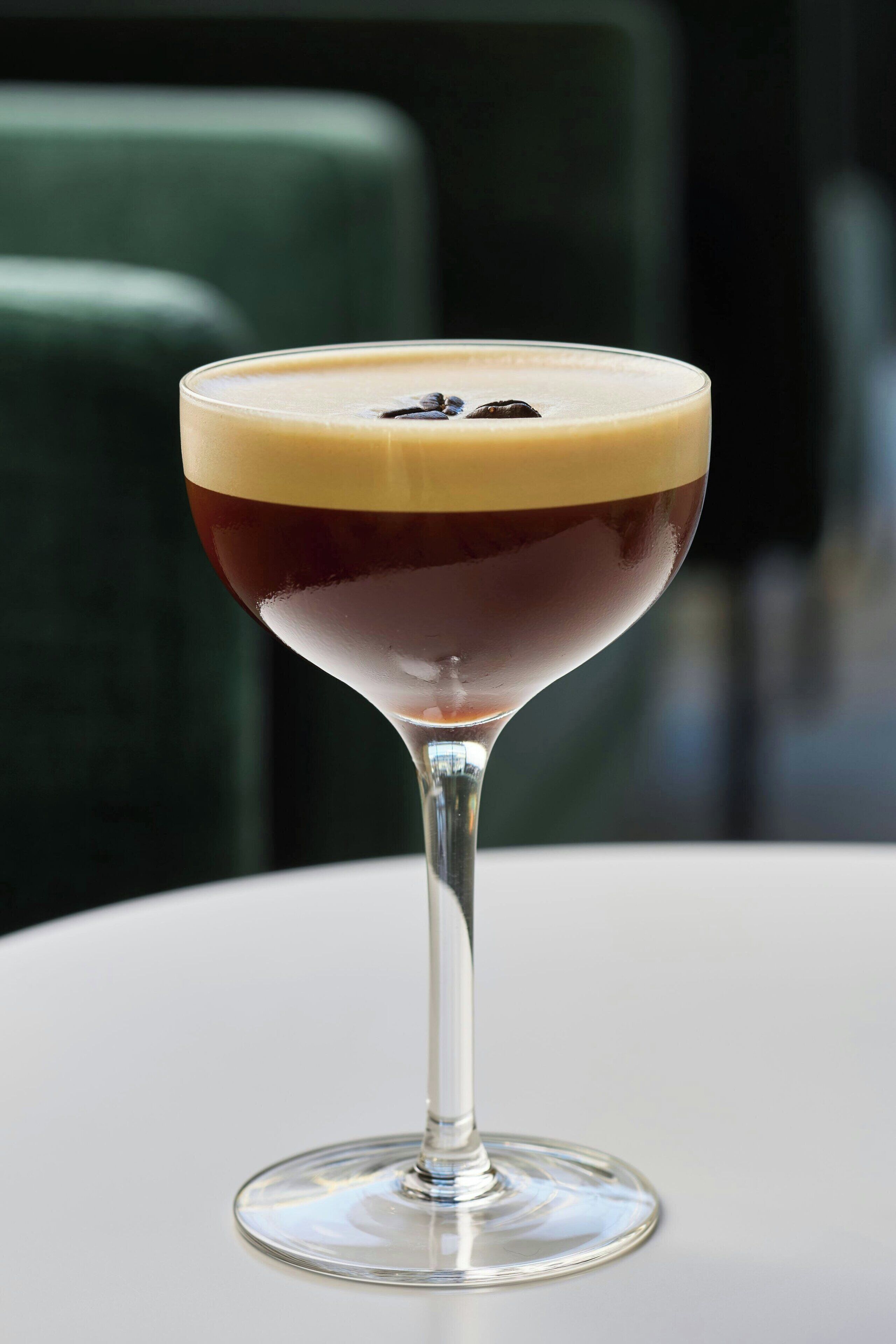 A cocktail in a martini glass on a white table.