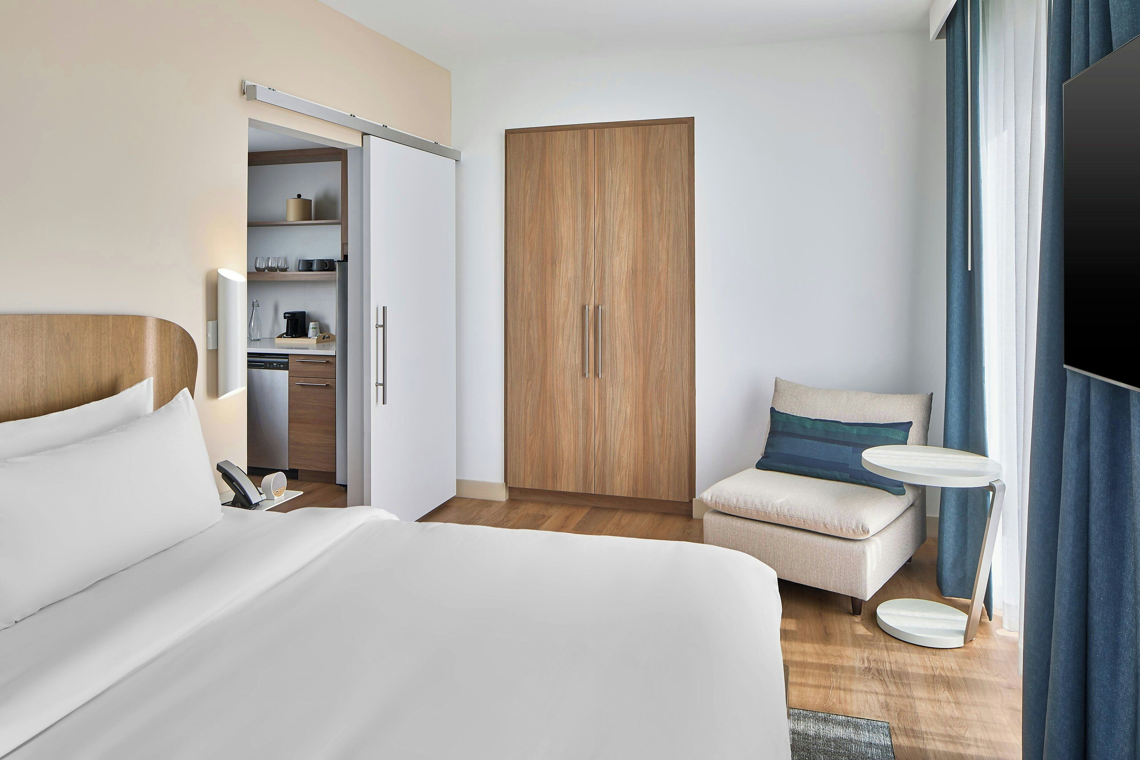 Une chambre d’hôtel avec un lit, un canapé, une télévision, une petite table et une armoire.
