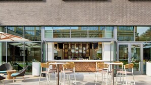 An outdoor bar area with a modern design, featuring a wooden bar counter and multiple seating options including wicker chairs and bar stools.