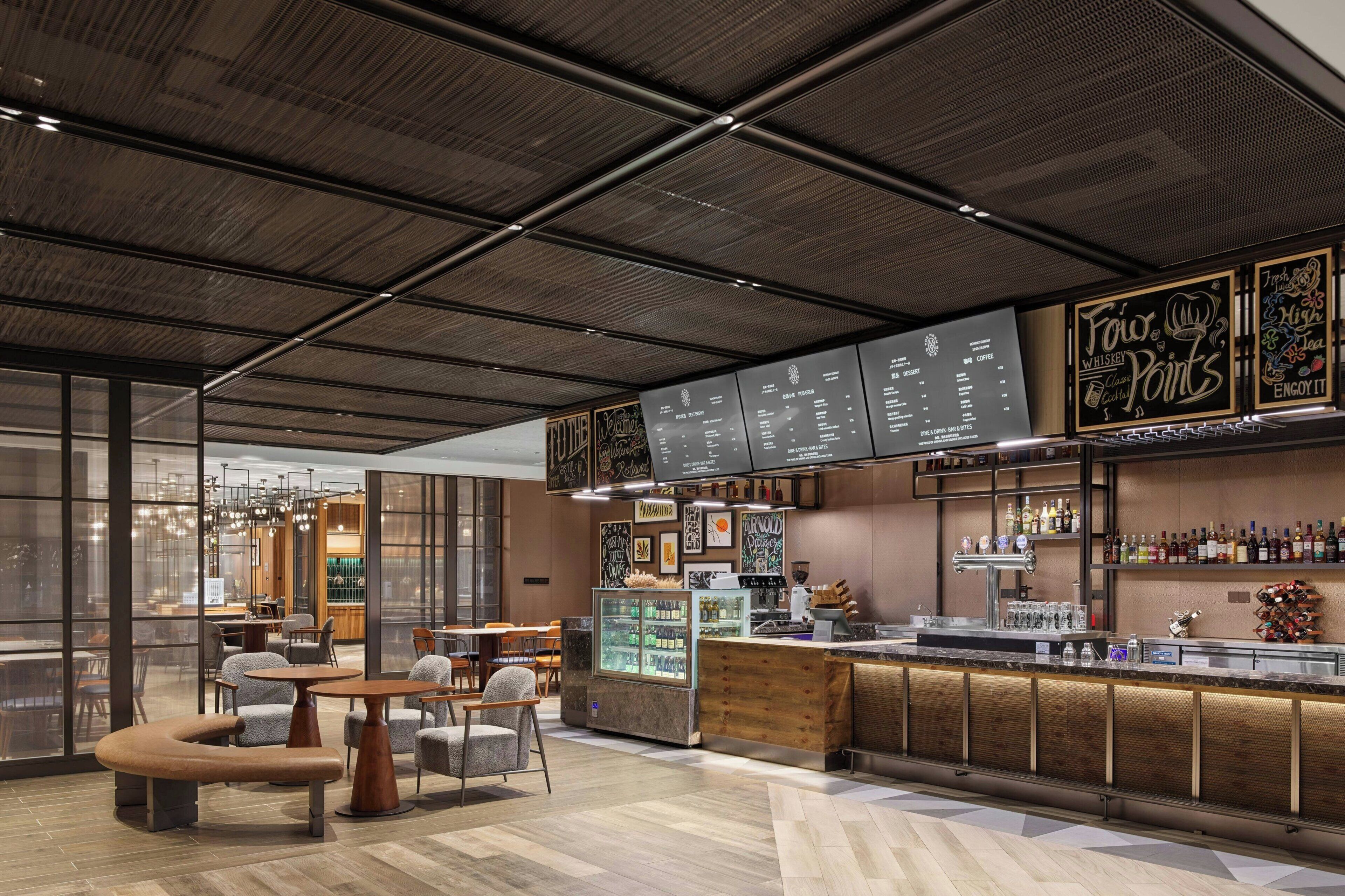 Un espace bar moderne doté d’un tableau affichant le menu, de sièges et d’un comptoir.
