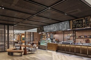 Un área de bar moderna con un tablero de menú, asientos y una barra.
