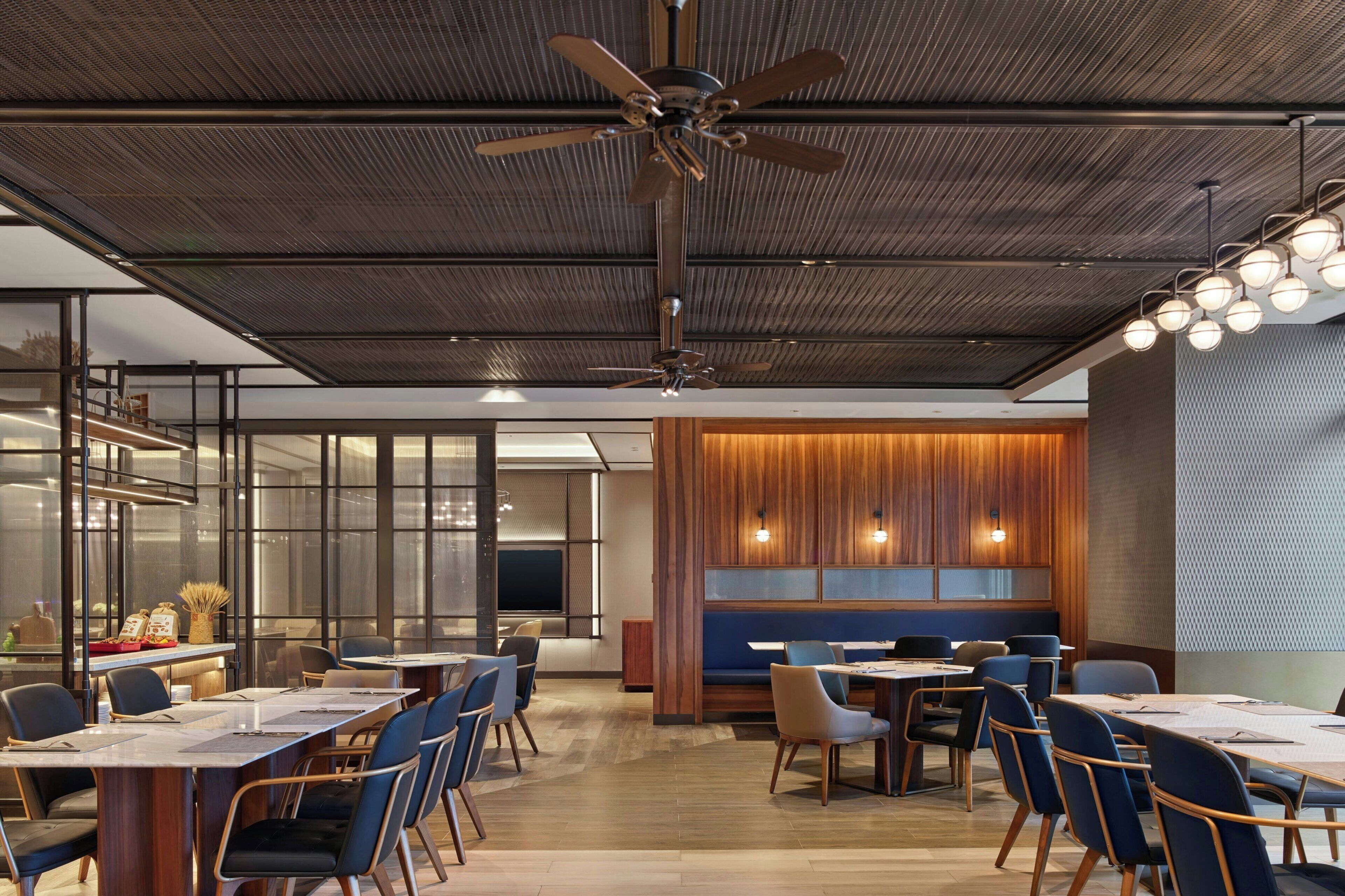 A modern conference room with tables, chairs, and a ceiling fan.