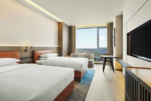 A hotel room with two beds, a sofa, a TV, and a view of the city. - Four Points by Sheraton Changzhou Economic Development Zone (Changzhou)