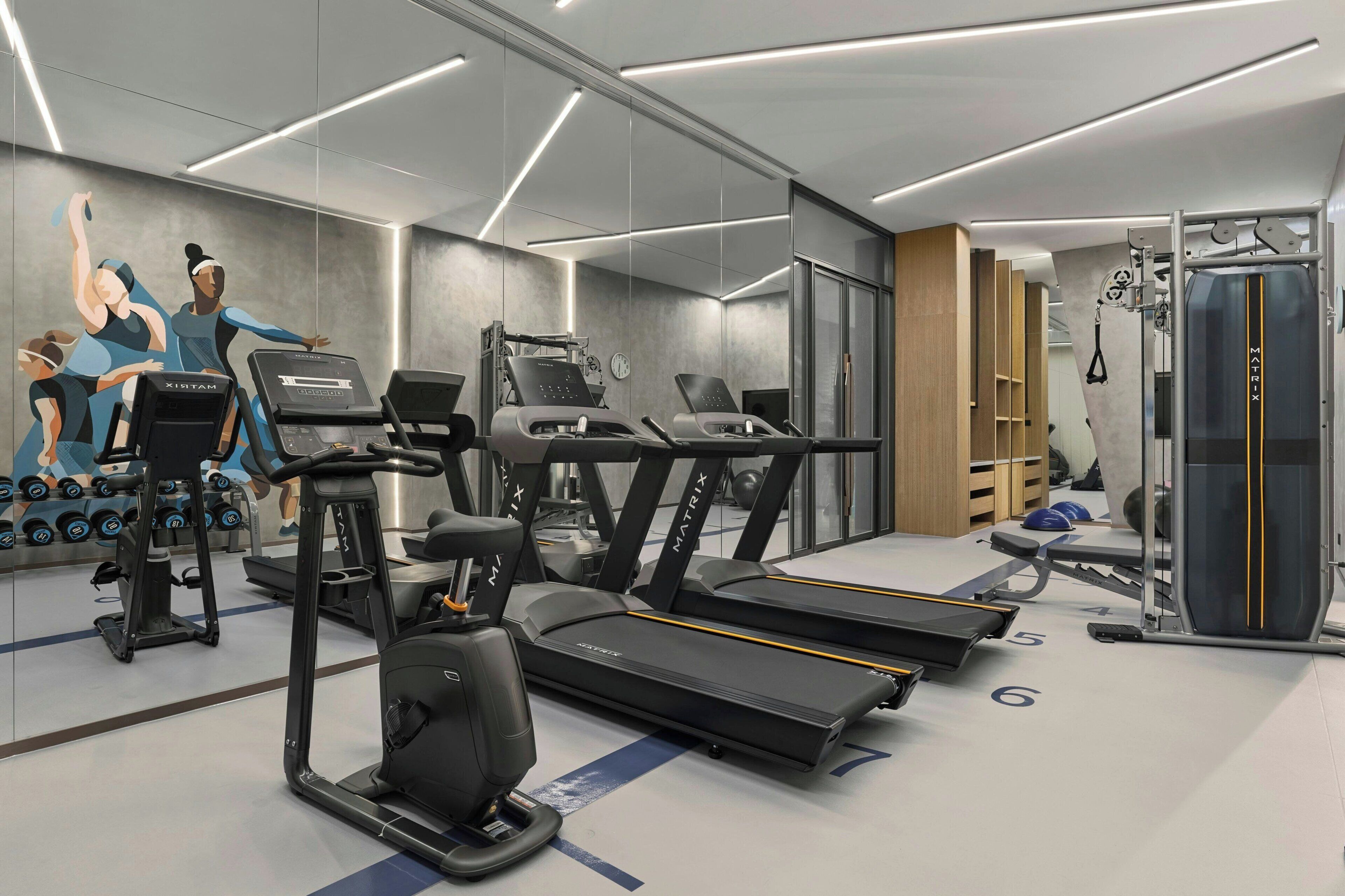 Ein modernes Fitnessstudio mit Laufbändern, Crosstrainern und Gewichten.
