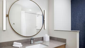 A modern bathroom with a round mirror, a sink, and a towel rack.