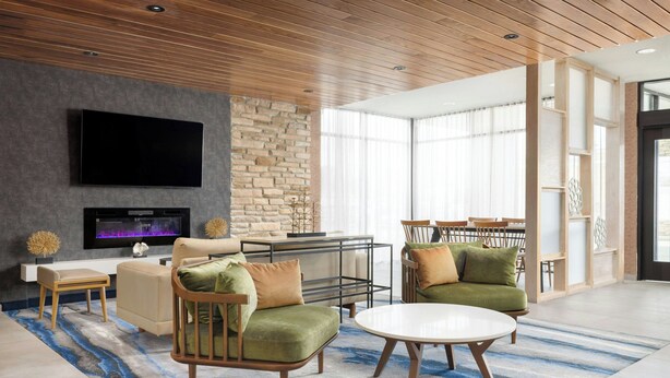 A modern living room with a flat-screen TV, comfortable seating, a fireplace, and a large window. - Fairfield by Marriott Inn & Suites Union (Union)