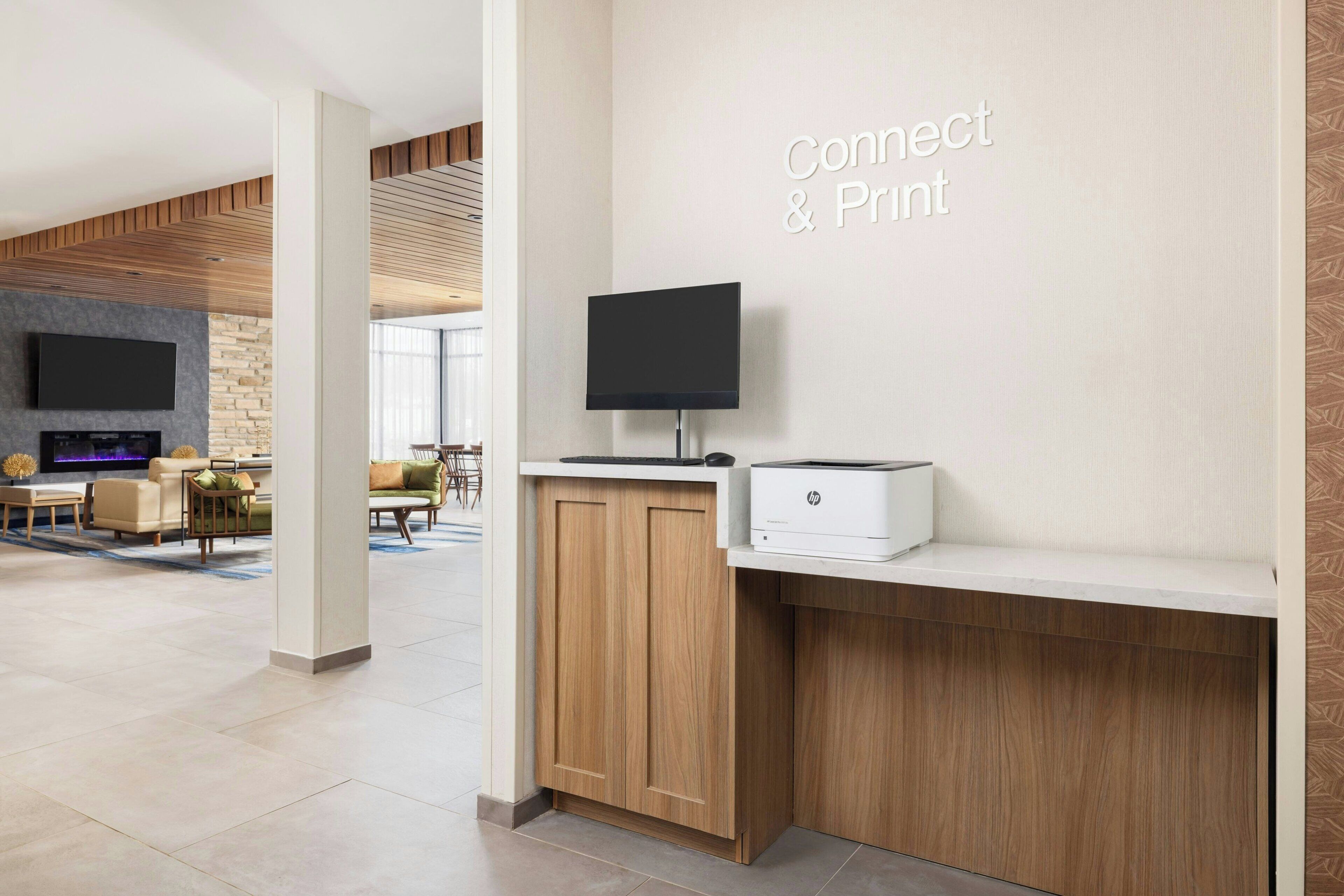 Ein moderner Empfangsbereich mit Flachbildfernseher, Drucker und einem Schild mit der Aufschrift 'Connect & Print'.