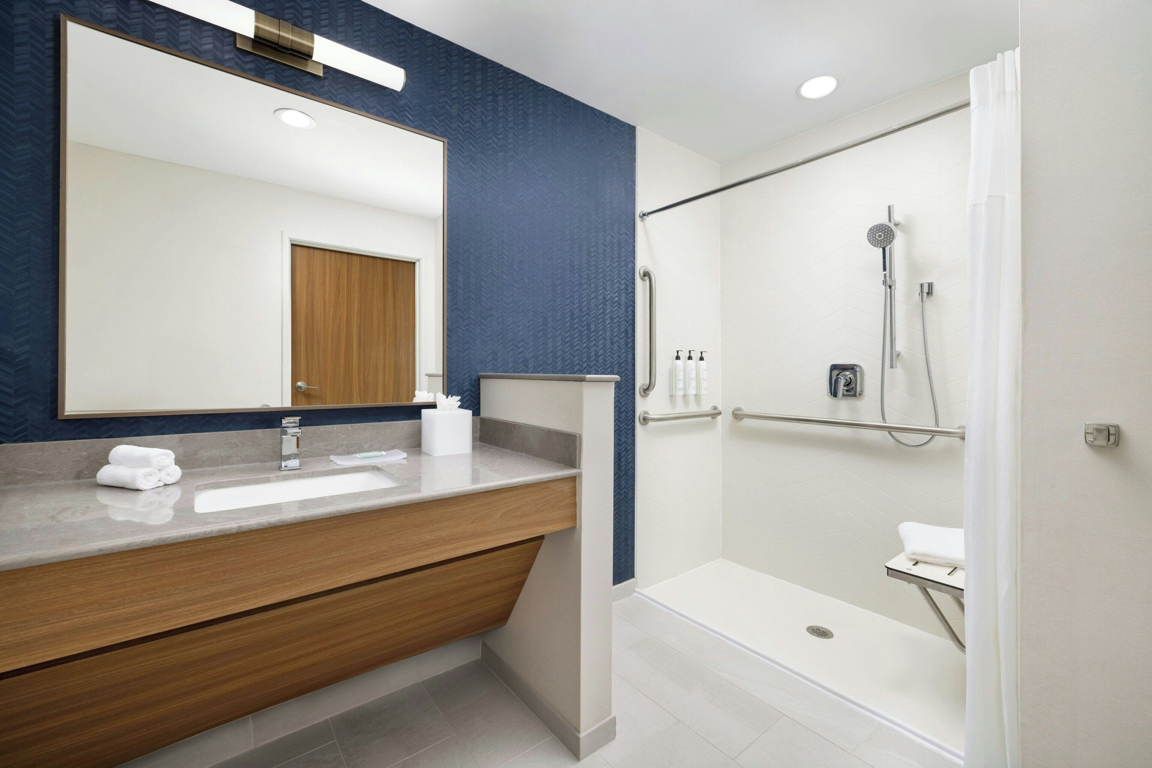 Een moderne badkamer met een grote spiegel, een houten wastafelmeubel en een inloopdouche.
