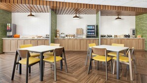 A modern kitchen with wooden cabinets, a central island, and yellow chairs around a white table. - Fairfield by Marriott Inn & Suites Union (Union)