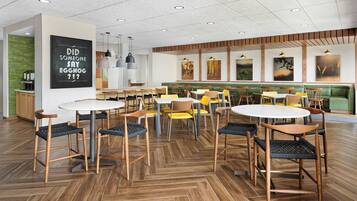 Un espace de restauration moderne avec un plancher en bois, des tables rondes et des chaises.