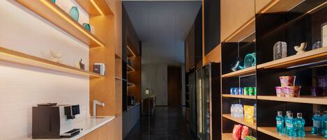 A modern kitchen with a coffee machine, shelves with various items, and a refrigerator.