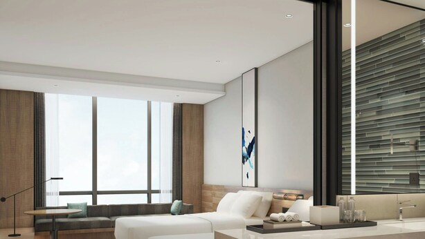 A modern hotel room with a large bed, a sofa, a desk, and a large mirror.