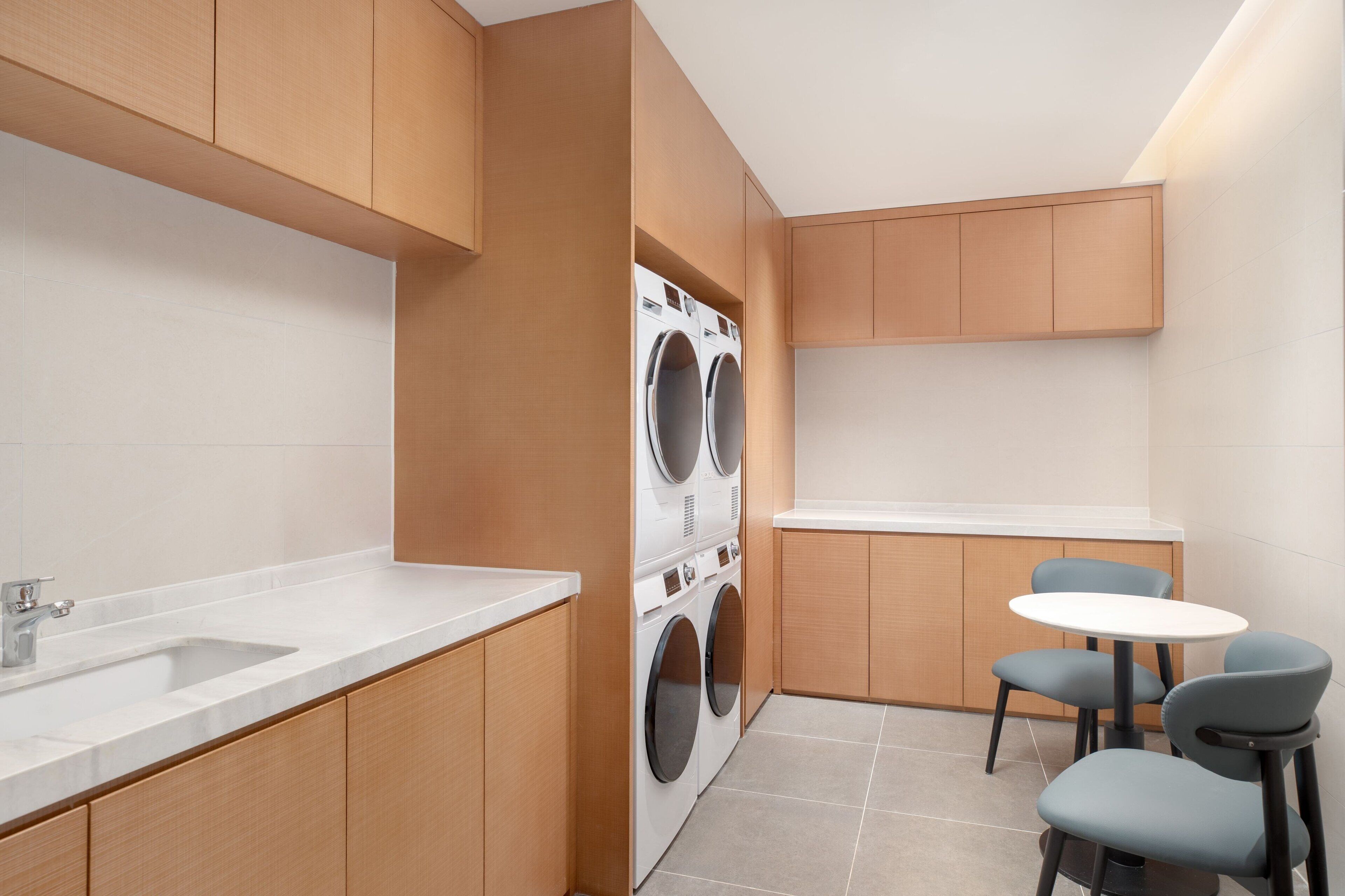 A compact kitchen with a built-in washer and dryer, a sink, and a small dining area with chairs.