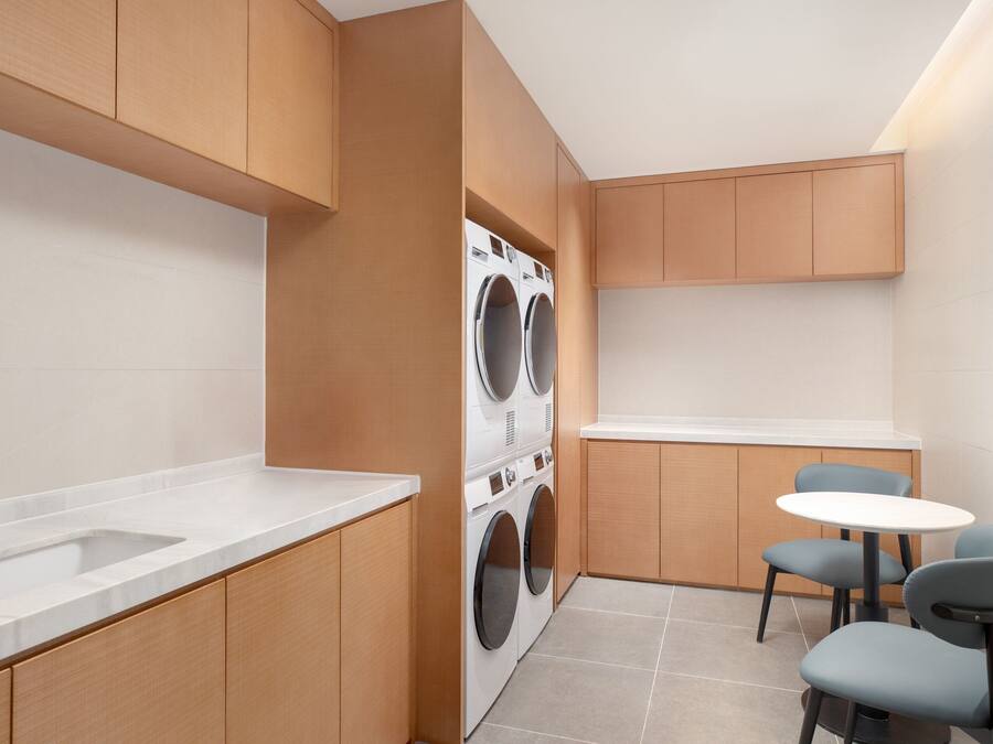 A compact kitchen with a built-in washer and dryer, a sink, and a small dining area with chairs.