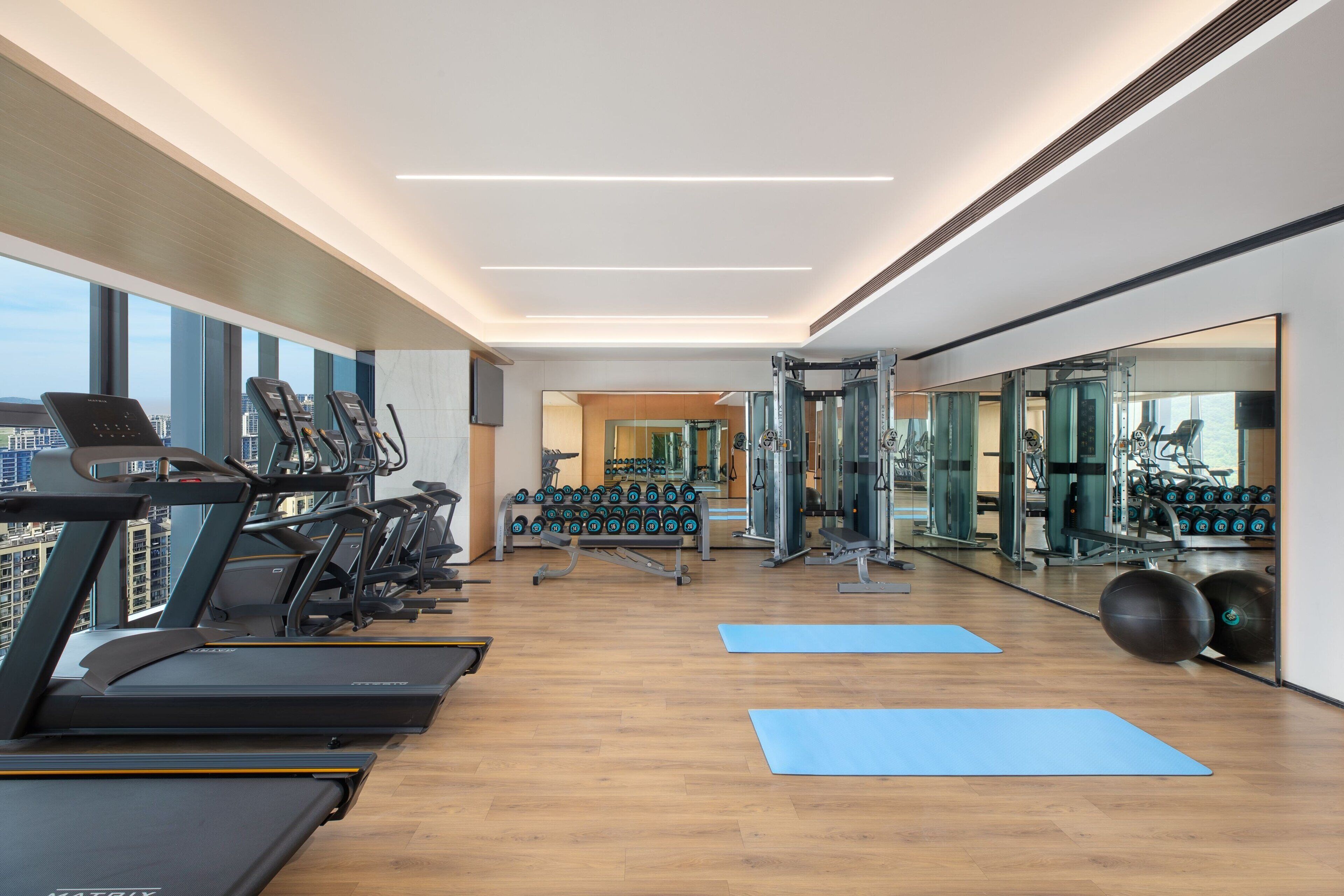 A modern gym with treadmills, weight machines, and yoga mats.
